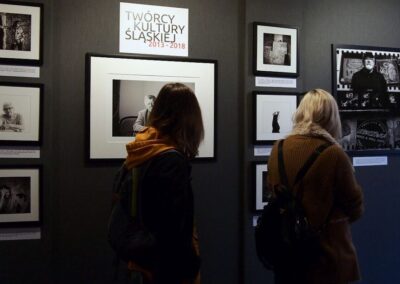 Dwie kobiety przygladające sie czarno-białym zdjęciom na wystawie Twórcy Kultury Śląskiej.